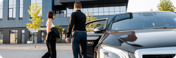 The chauffeur opens the door for a business traveler during a corporate transfer.