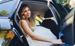 Young woman in formal gown exiting a car for prom or graduation.